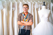© CandyRetriever  - Portrait of Asian LGBTQ guy bridal shop owner using tape measure measuring wedding dress on sewing mannequin at wedding studio. Small business entrepreneur wedding planner and tailor designer concept