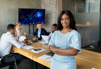 Poster - Modern Entrepreneur. Black Businesswoman Posing In Conference Room During Meeting With Colleagues