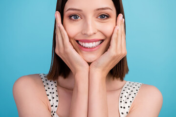 Wall Mural - Cropped photo of charming pretty lady hands cheeks shiny smile wear dotted overall isolated blue color background