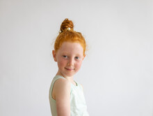 Head And Shoulders Of Little Girl Looking Over Her Shoulder On Plain White Background