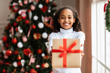 Wall Mural - Black Girl Holding And Giving Christmas Gift At Home