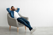 © Prostock-studio - Calm young Arab man relaxing in armchair against white studio wall, copy space