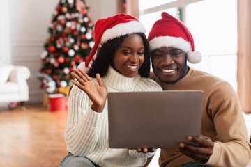 Wall Mural - Happy festive black family using tablet making videocall on Xmas