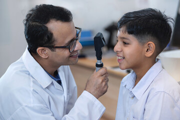 Optometrist is examining the eyes of an Indian boy, ophthalmologist uses special device to examine the boy's vision