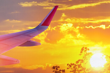 Wall Mural - wing of an airplane flying at sunset, morning time. the concept of the freedom journey