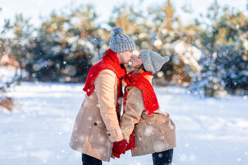 Playful man and woman kissing while walking by winter park