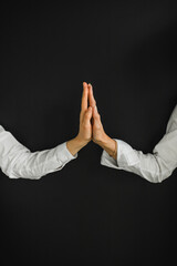 The two women's hands touched palms. A sign of friendship, love, peace, and acceptance. Black background and white clothes.