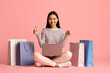 © Prostock-studio - Happy Asian Woman Sitting With Laptop Among Shopping Bags, Showing Thumbs Up