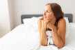 © spyrakot - Young smiling attractive brunette woman lies in a big white bed