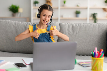 Poster - Girl sitting on sofa, using laptop showing thumbs up