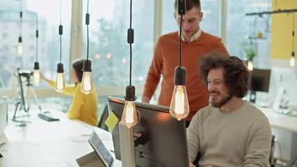Co-workers developers looking at computer screen while discussing online information