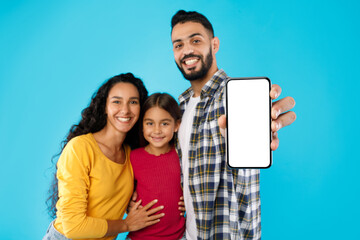 Middle-Eastern Family Showing Cellphone With Empty Screen Over Blue Background