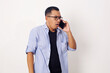 Asian man in casual look shocked while talking on phone. Half body studio shots against white background