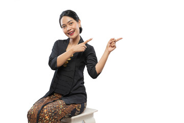 beautiful woman wearing traditional Javanese clothes pointing copy space