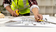 © kamiphotos - A design engineer, an architect, he is using a tape measure to measure the building plans he has designed to check and correct. House and building design concepts by professional architects.