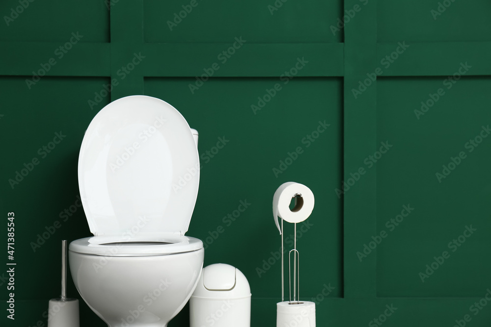 Toilet bowl with bin and paper rolls near green wall