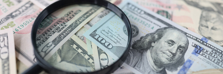 Wall Mural - One hundred dollar bills and magnifying glass lie on table closeup