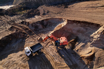 Wall Mural - Mining excavator load the sand into dump truck in open pit. Developing the sand in the opencast. Heavy machinery on earthworks in quarry. Mining truck transports sand from open-pit mining.