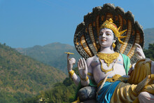 A Sculpture Of The Indian Supreme God Vishnu On The Banks Of The Ganges River In Rishikesh - A Place Of Pilgrimage For Hindus, The Capital Of Yoga, A Popular Tourist Destination In India.