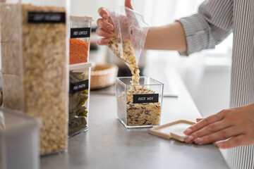 Wall Mural - Closeup hands housewife adding rice mix from package into transparent case box with title sticker