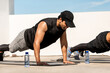 © Atstock Productions - Young Indian man doing bodyweight push up exercise outdoors on building rooftop with friend