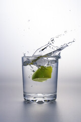 Wall Mural - Lime clove splashing into a glass of water.