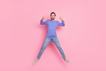 Wall Mural - Full size photo of brunet impressed millennial guy jump show thumb up wear blue pullover jeans shoes isolated on pink background