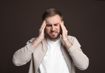 Sticker - Young man suffering from headache on dark background