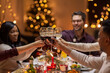 © Syda Productions - holidays, party and celebration concept - multiethnic group of happy friends having christmas dinner at home and drinking wine