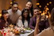 © Syda Productions - photographing, holidays and celebration concept - close up of woman with smartphone taking picture of her happy friends at christmas dinner