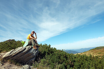 Wall Mural - Tourist with backpack on cliff in mountains. Space for text