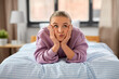 © Syda Productions - emotion, expression and people concept - girl lying on bed at home and making face