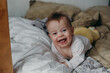 © Татьяна Ивашкова - a happy baby in a white bodysuit is lying on the bed