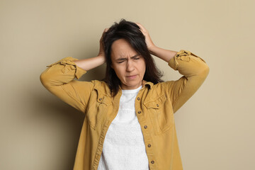 Wall Mural - Mature woman suffering from headache on beige background