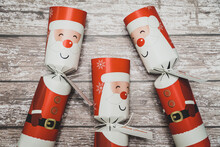 Three Santa Christmas Crackers On A Grey Wooden Background