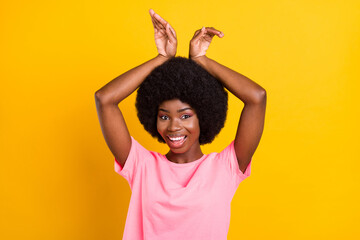 Poster - Photo of young african girl happy positive smile fooling show hands bunny ears isolated over yellow color background