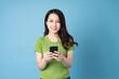 © Q88 - portrait of young asian girl, holding phone, isolated on blue background