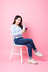 Wall Mural - portrait of beautiful asian girl sitting in chair, isolated on pink background