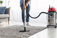 Low Section Of Woman Cleaning Rug Carpet With Vacuum Cleaner