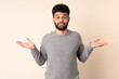 © luismolinero - Young Moroccan man isolated on beige background having doubts while raising hands