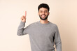© luismolinero - Young Moroccan man isolated on beige background pointing up a great idea