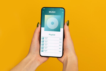 Female Hands Holding Smartphone With Opened Music Player Playlist On Screen