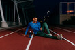 © ADDICTIVE STOCK - Athlete using phone and sitting on the floor of the running track