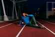 © ADDICTIVE STOCK - Athlete using phone and sitting on the floor of the running track