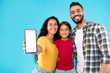 Wall Mural - Arab Family Showing Cellphone Screen To Camera Over Blue Background