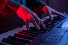 Male Hands Playing Electric Digital Piano. Musician Man With Black Guitar At A Rock Concert