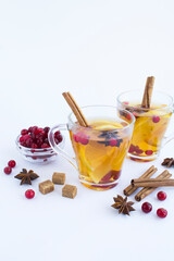 Wall Mural - Hot tea with lemon, cinnamon, cranberry and anise in the glass cups on the white background. Close-up. Winter drink.