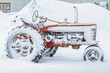 An old antique tractor covered in snow.