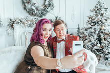 LGBTQ Lesbian Homosexual Couple Celebrating Christmas Or New Year. Gay Young Lady Female Woman With Butch Partner Taking Selfie Or Chatting On Phone In Social Media.