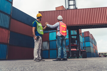 Wall Mural - Industrial worker works with co-worker at overseas shipping container yard . Logistics supply chain management and international goods export concept .